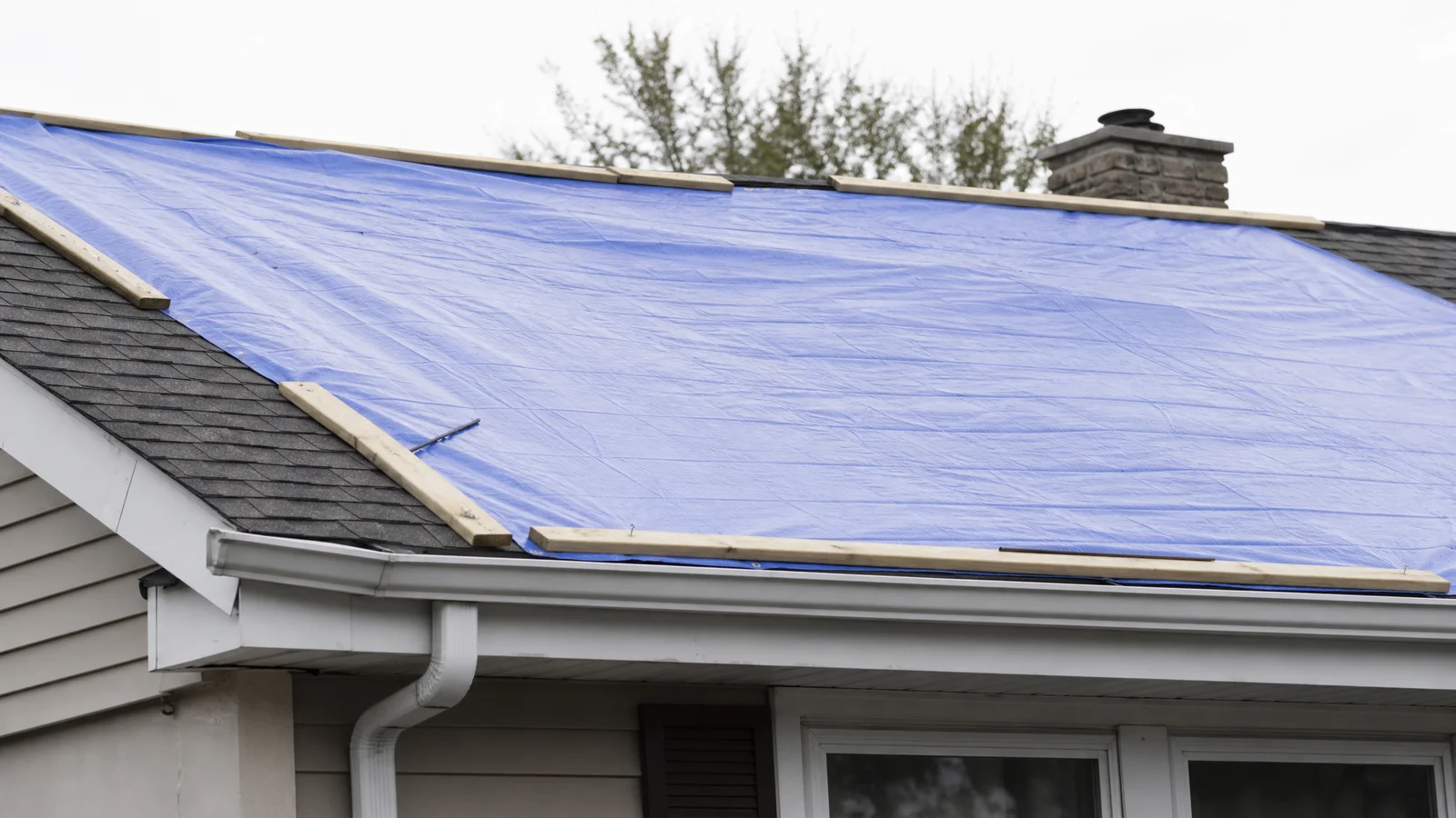 Emergency tarp secured over damaged roof section