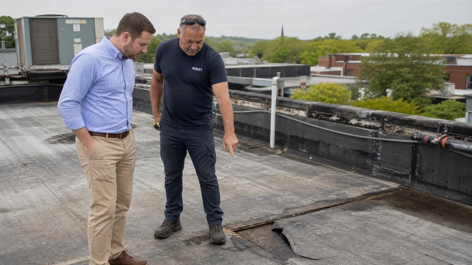 Property manager and roofer reviewing a flat roof
